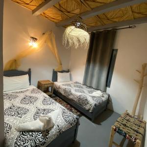 ein Schlafzimmer mit zwei Betten und einem Kronleuchter in der Unterkunft Auberge Etoile Filante d Or Ait Ben Haddou in Aït-Ben-Haddou + 57 Fotos