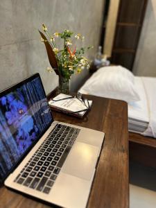 Ban Nong WaiにあるKad Sala Homestayの花瓶が置かれた木製のテーブルの上にノートパソコンが置かれている