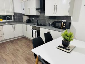 a kitchen with white cabinets and a table with a plant on it at Modern 1BR Home in Clayton-le-moors in Clayton le Moors