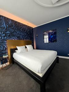 ein Schlafzimmer mit einem großen Bett und einer blauen Wand in der Unterkunft LOGIS Hôtel Borel in Dunkerque