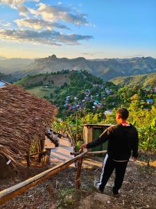 une femme debout au sommet d'une colline regardant une vallée dans l'établissement Homestay Nunga หนูหง่าโฮมสเตย์, à Mae Hong Son