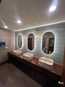 uma casa de banho com três lavatórios e três espelhos em Hatyai Merridian Hotel em Hat Yai