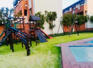 einen Spielplatz mit Rutsche neben einem Pool in der Unterkunft Sandton Skyline Suite - 2 Bedroom Apartment in Sandton