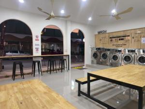uma lavandaria com máquinas de lavar roupa, uma mesa e bancos em Hatyai Merridian Hotel em Hat Yai