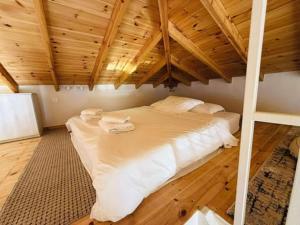 a large white bed in a room with a wooden ceiling at Aegean View Apartment in Skala Eresou