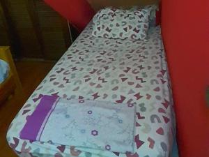 a small bed in a red room with a bedspread on it at Avec piscine 06-17-61-38-73 in Ifrane +1 photo