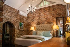ein Schlafzimmer mit einer Ziegelwand mit einem Bett in der Unterkunft Tarry-Stone Cottages in Dullstroom