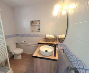 un bagno con un water, un lavandino e uno specchio di Candela con amor a Punta Umbría