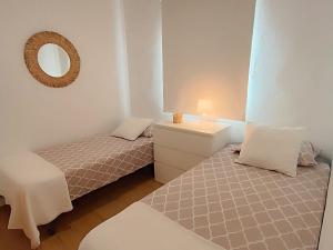 una piccola camera con due letti e uno specchio di Candela con amor a Punta Umbría