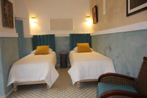 zwei Betten in einem Zimmer mit grünen Vorhängen in der Unterkunft Palais el Abbassia in Marrakesch