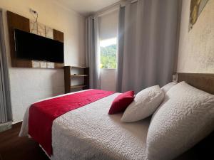 een slaapkamer met een bed met rode en witte kussens bij Recanto Guaraú 2 in Peruíbe