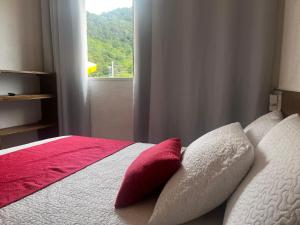 een bed met rode en witte kussens en een raam bij Recanto Guaraú 2 in Peruíbe
