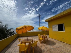 2 tafels en stoelen met parasols op een balkon bij Recanto Guaraú 2 in Peruíbe