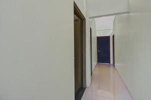 un couloir avec des murs blancs et une porte noire dans l'établissement Hotel O King's Inn, à Dhantoli