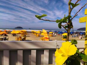 een strand met gele parasols, tafels en stoelen bij Recanto Guaraú 2 in Peruíbe +8 foto's
