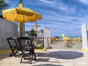 a table and chairs under a yellow umbrella on the beach at peruibe pousada na areia in Peruíbe