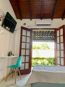 Cette chambre comprend un lit et une chaise verte. dans l'établissement Hotel Colonial Lençois, à Lençóis Paulista