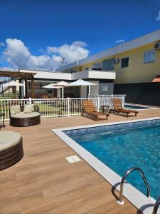 einen Pool auf einer Terrasse mit Stühlen und einem Gebäude in der Unterkunft Apto 250mt Praia Coroa Vermelha 2 Quartos com Ar Condicionado in Porto Seguro