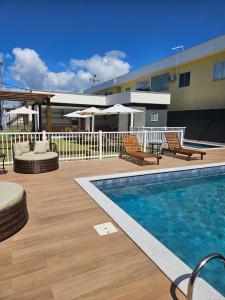 eine Terrasse mit einem Pool und Stühlen sowie ein Gebäude in der Unterkunft Apto 250mt Praia Coroa Vermelha 2 Quartos com Ar Condicionado in Porto Seguro