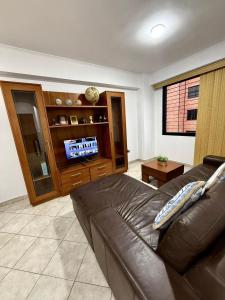 ein Wohnzimmer mit einem Ledersofa und einem TV in der Unterkunft Located in the heart of Mañongo in Naguanagua