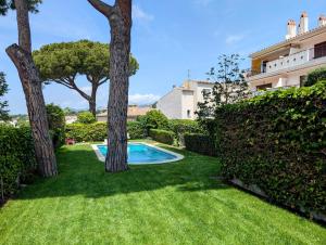a yard with a swimming pool and two trees at Apartamento Playa in S'Agaro