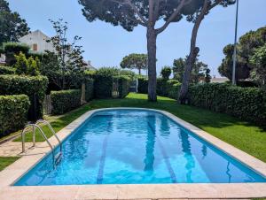 a swimming pool in a yard with trees at Apartamento Playa in S'Agaro