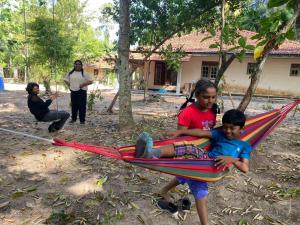 Ein paar Kinder sitzen in einer Hängematte in der Unterkunft The Ceylon Olive Resort in Katunayaka