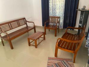 ein Wohnzimmer mit drei Holzbänken und Stühlen in der Unterkunft The Ceylon Olive Resort in Katunayaka