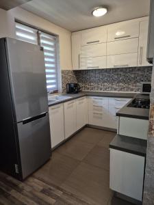 a kitchen with white cabinets and a stainless steel refrigerator at Апартамент Top Central in Yambol