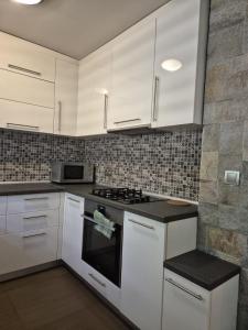 a kitchen with white cabinets and a stove top oven at Апартамент Top Central in Yambol
