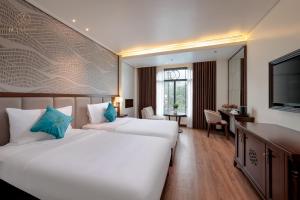 a hotel room with two beds and a desk at De La Mont Hotel Ha Giang in Ha Giang