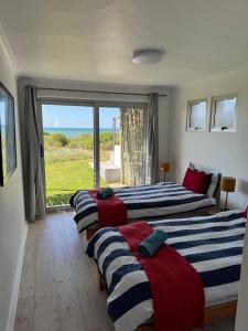three beds in a room with a view of the ocean at Witbaai Beach House in Britannia Bay