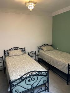 Riad Nora - Confort, Calme & Sécurité في مراكش: سريرين في غرفة نوم مع ثريا