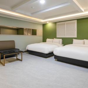 two beds in a room with green walls at 와이케이호텔 in Suwon +8 photos