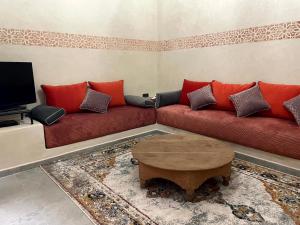 Riad Nora - Confort, Calme & Sécurité في مراكش: غرفة معيشة مع أريكة حمراء وطاولة قهوة