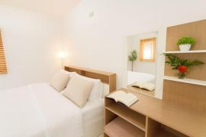 Schlafzimmer mit einem Schreibtisch und einem Bett mit weißer Bettwäsche in der Unterkunft Dalbit Thai Stay 2 Bedroom Patong house - 8mins walk to Jungcyelon Bangla Rd in Patong Beach