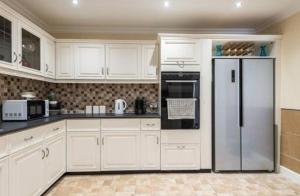 a kitchen with white cabinets and a refrigerator at Luxury 4BR, Free Parking, Near Beach, Sleeps 8 in Edinburgh