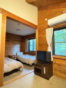 a bedroom with two beds and a flat screen tv at 蔵王ペンション kobaya in Kaminoyama