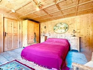 a bedroom with a pink bed in a room with wooden walls at Haus Freistabl - Uriges Bauernhaus für 6 Personen mit Sauna & Bergblick im Ötztal in Sölden