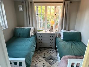 two twin beds in a small room with a window at Peaceful Garden Cottage in Birmingham +10 photos