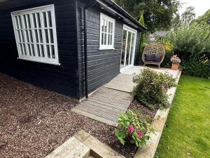 a small black house with a wooden porch and a chair at Peaceful Garden Cottage in Birmingham