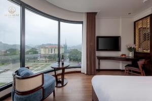 a hotel room with a person sitting in a chair and a bed at De La Mont Hotel Ha Giang in Ha Giang