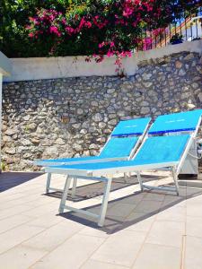 a blue lounge chair sitting next to a stone wall at Alisea Home in Nerano
