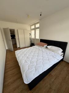 a large white bed in a room with wooden floors at PRV Apartment 2 in Künzelsau +2 photos