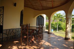 a wooden table and chairs on a patio at Cozy 1-BR Garden Cottage near Diani Beach in Galu +9 photos