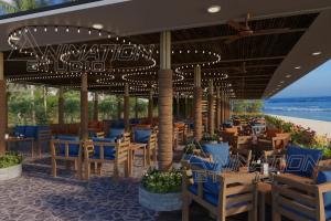 un restaurant avec des chaises et des tables bleues sur la plage dans l'établissement Trishvam Palolem Beach Resort, à Canacona