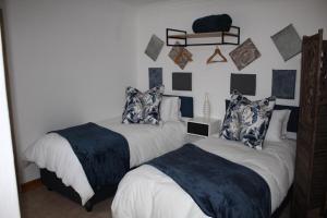 a bedroom with two beds and a shelf on the wall at Cottage of Grace in Benoni