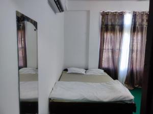 1 dormitorio con cama, espejo y cortinas en GoFam, en Dibrugarh 9 fotos más