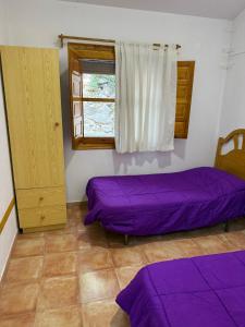a room with two purple beds and a window at Casas Rurales La Navela in Blanca