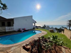 a swimming pool in front of a house with the ocean at Casa Bellé Bluff in Durban